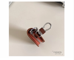 Dettaglio dell'astuccio per chiavi in pelle marrone con motivo litchi e moschettone