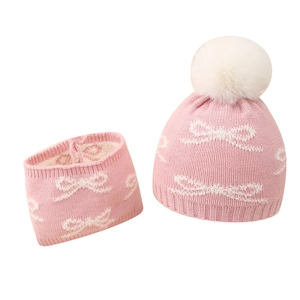 Pink baby winter knit hat and scarf set with white bow patterns and pom-pom detail