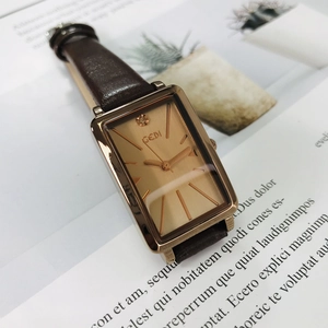 Detailed view of women's rectangular watch with rose gold dial and brown leather strap