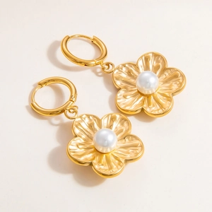 Minimalist gold stainless steel flower earrings with white pearls on a beige background