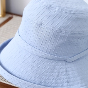Détail d'un chapeau cloche bleu clair avec large bord et texture tissée en relief