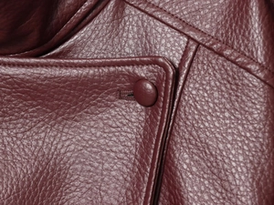 Macro detail of wine red faux leather jacket showing premium grain and matching buttons