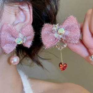 Detail of pink bow earrings with pearls, rhinestones and a red heart gemstone