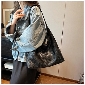 Close-up of black woven leather tote bag showing intricate craftsmanship and wide strap