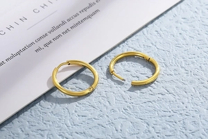 Detailed macro view of small gold stainless steel hoop earrings with a hinged closure