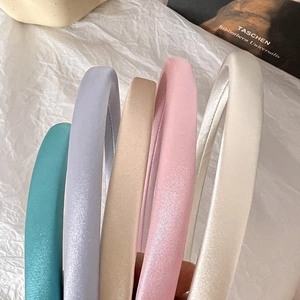 Close-up of five colorful satin padded headbands showing silky smooth texture and soft sheen