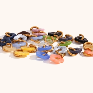 Macro detail of multi-colored acrylic flower charms on 18K gold plated hoop earrings