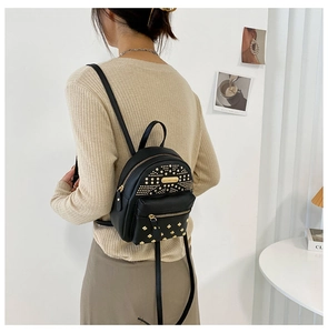 Detailed view of black mini backpack with gold studs and earphone port on model