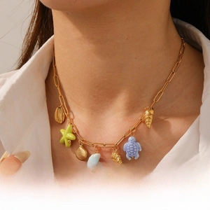 Detail of gold seashell necklace with starfish turtle pendants on model neck