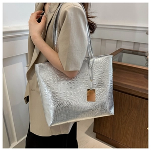 Close-up of silver tote bag featuring crocodile pattern texture and golden metal charm