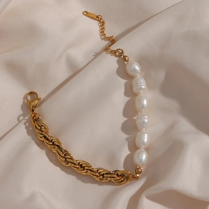 Detailed close-up of half-gold chain and white baroque pearls on yellow silk fabric