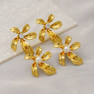 Close-up of gold flower earrings with sparkling rhinestones and elegant pearls