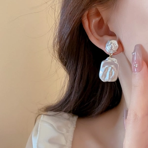 Detailed view of baroque pearl star earrings on model with elegant gold metal accents