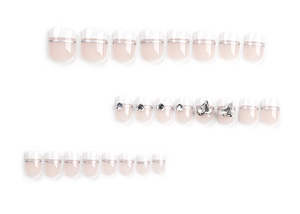 Detail of French press-on nails with white tips, pink base, and heart rhinestone accents