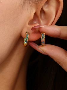 Macro shot of gold hoop earrings with multi-colored pavé-set crystals on model ear