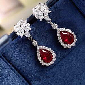 Macro shot of silver-plated waterdrop earrings with red gems in a blue velvet box