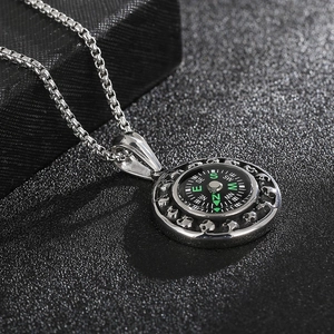 Macro view of silver compass pendant with skull relief and green dial on box chain