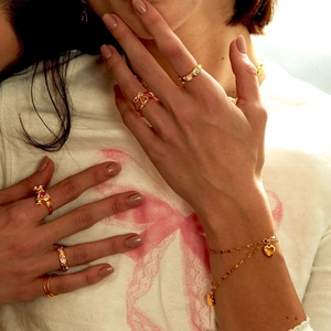 Close-up of luxury gold-plated rings and heart bracelets on hand with pink gemstones