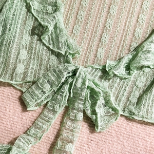 Close-up of mint green lace cover-up with floral pattern and ruffled hem details