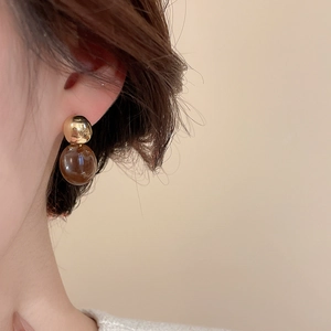 Gros plan de boucles d'oreilles rétro avec clous dorés et sphères en ambre