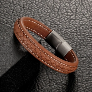 Brown braided leather bracelet with stitching and dark magnetic steel clasp on dark surface