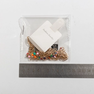 Fashionable colorful beaded necklace with gold chain next to ruler for size reference