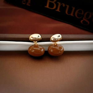 Macro detail of vintage gold-plated drop oil earrings with smooth enamel finish