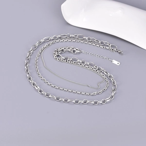 Silver layered Cuban and link chain necklace for women on a white ceramic display