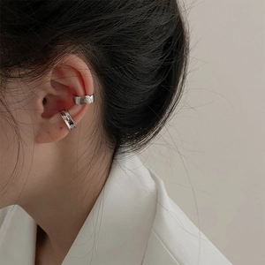 Detail of silver textured ear cuffs with hammered finish worn on the ear cartilage