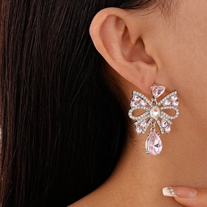 Close-up of pink crystal bow earrings with hanging water drop tassel on a model
