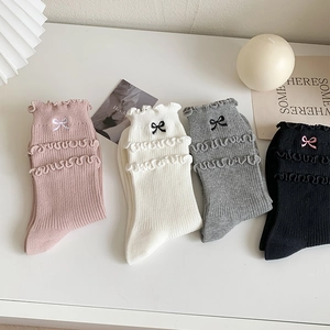 Detail of ruffled edges and small embroidered bows on colorful cotton JK crew socks