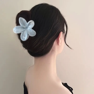 Detail view of a large blue gradient flower hair claw clip worn on a half-up hairstyle