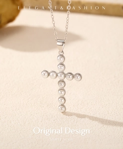 Gros plan d'un pendentif croix en argent s925 avec onze perles blanches brillantes