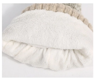Detailed view of the thick white fleece lining and beige cable knit texture on the winter hat