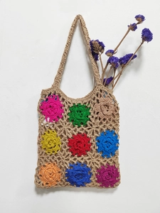Macro detail of hand-knitted tote bag featuring colorful crochet flower patchwork patterns
