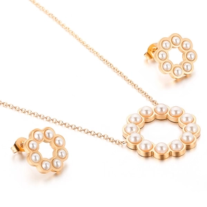 Set collana floreale dorata traforata e orecchini a perno con perle su sfondo bianco