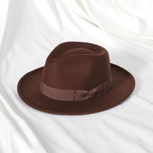 Detailed view of dark brown felt fedora hat with satin ribbon and bow on silk fabric