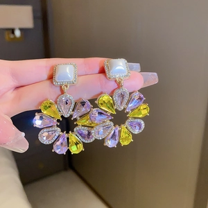 Detailansicht von Perlenkette und Blumenohrringen mit gelben und lila Kristallen