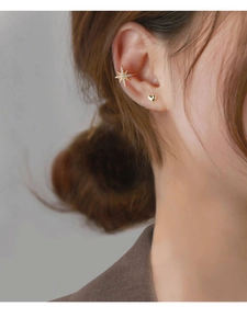 Close-up of a sparkling star ear cuff and heart stud earring set on a model