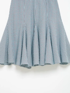Detail shot of the wavy hemline on this blue and black gingham midi skirt with pleats