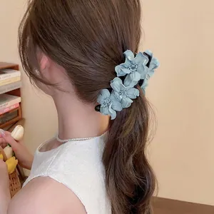 Pince à cheveux élégante avec fleurs en tissu bleu-gris sur une queue de cheval