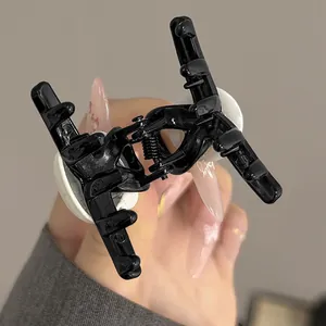 Close-up of a large glossy black acrylic hair claw clip with a strong metal spring