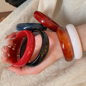 Close-up of resin chunky bangles in red, black, navy, amber, and cream colors