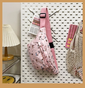 Pink cartoon dog print chest bag displayed on a white pegboard in a cozy room setting