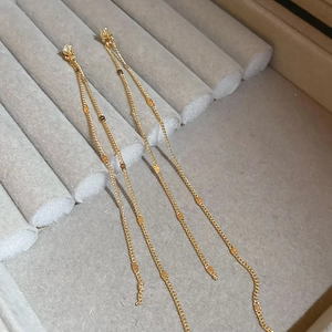 Detail of long gold tassel earrings with zircon studs and hanging metallic sequins