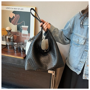 Detailed view of black woven leather tote bag with classic textured finish in a home setting