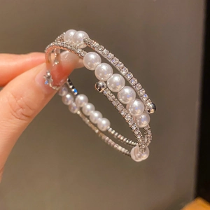 Detailansicht eines mehrlagigen Spiralarmreifs mit Perlen und Kristallen an der Hand