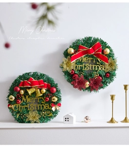 Close-up of artificial pine wreath with red bows, gold baubles and Merry Christmas sign