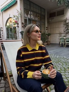 Detail of preppy style striped polo knit top with contrasting yellow collar and buttons