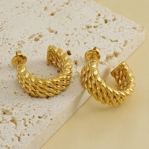 Fashionable 18k gold twisted rope C-shaped hoop earrings on a textured stone display